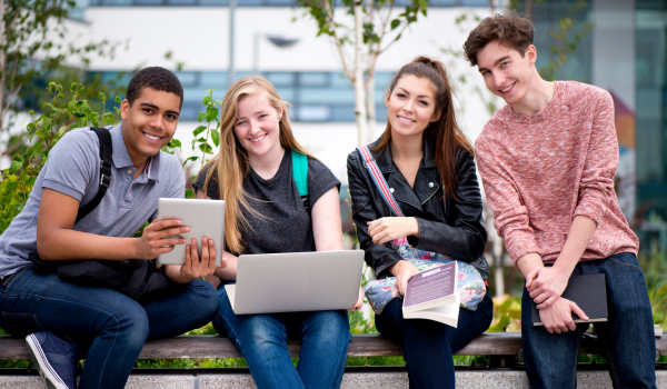 4 students sit outside on a bench