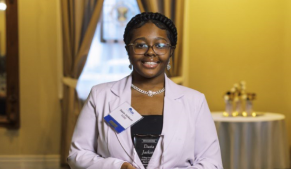 Student holding an award smiling at the camera