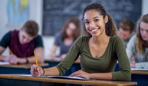 a student at a desk smiling into the camera