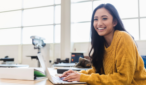 a student in a science laboratory smiles at the camera