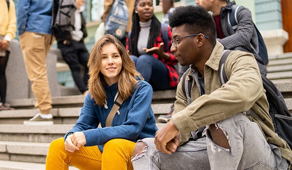 two students sitting on steps outside a college building