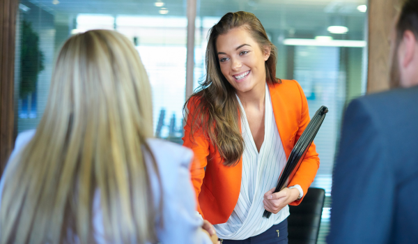 a young woman with a file folder shakes hand with two older individuals