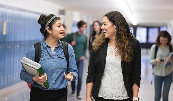 student and teacher walking together down school hallway